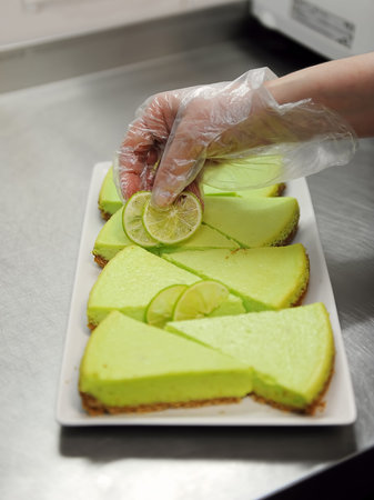 Confectioner is decorating lime cake in kitchenの写真素材