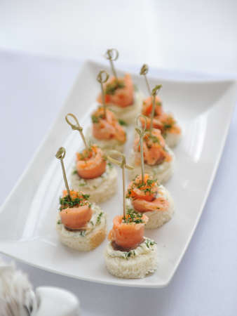 Canapes with salmon, batter, cream cheese and fennel on white plateの写真素材