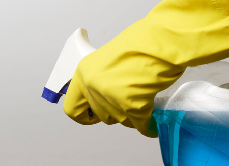 Hand in yellow glove holding spray bottle