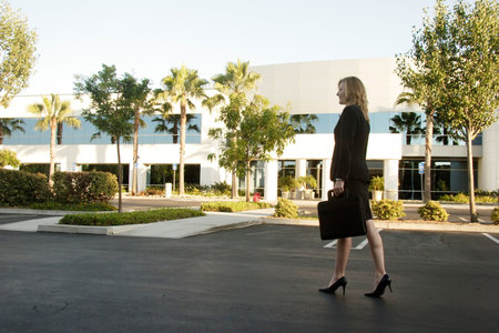 Business woman walking through parking lot carrying briefcaseの写真素材