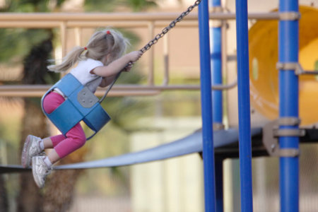 Little three year old girl on a swimg at the park