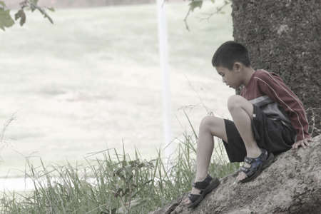 Boy sitting on a rock at the parkの写真素材