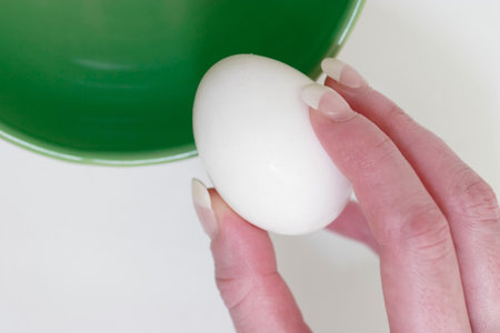 Hand holding an egg about to crack it into a bowl