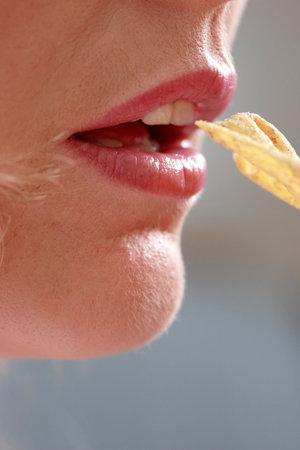 Close--up of womans mouth about to eat a chipの写真素材