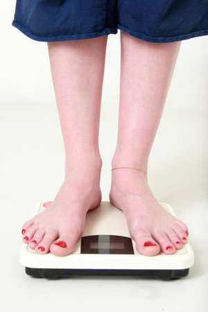 womans feet standing on a scale on white