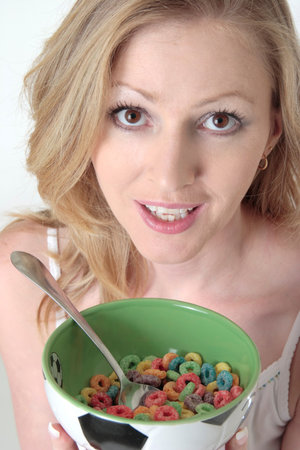 woman eating a bowl of colourful cereal from a green bowl lifestyle shotの写真素材