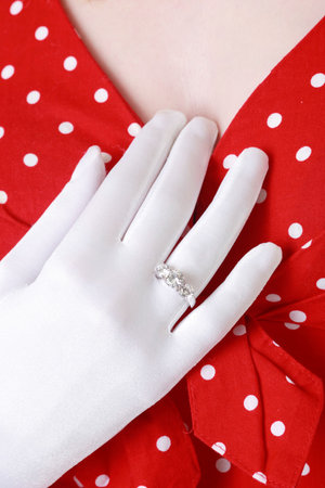 Woman showing her diamond ring with hand on chest wearing white gloveの写真素材