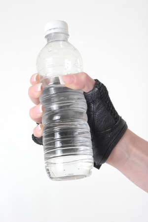 Hand holding a bottle of water wearing a black weight lifting gloveの写真素材