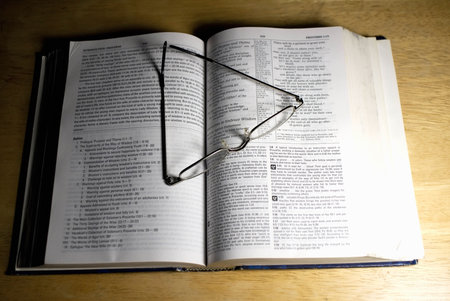 pair of reading glasses on open bookの写真素材