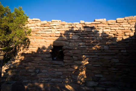 stone wall with shadows of trees and blue skyの写真素材