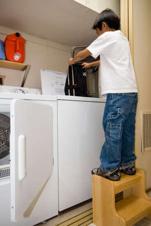 Young independent asian boy doing his own laundryの写真素材
