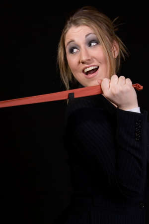 Attractive young blonde Business woman pulling on a man's tie laughing standing on blackの写真素材