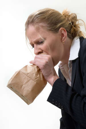 Blond woman holding a brown paper bag over mouth with a distraught expression as if having a panic attack or being nauseated Blond woman holding a brown paper bag over mouth with a distraught expression as if having a panic attack or being nauseated