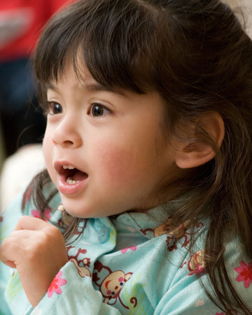 Face of an adorable little three year old brunette girl in pyjamas laughing