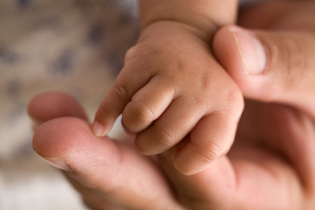 Tiny newborn baby fingers wrapped around adult female fingers up closeの写真素材