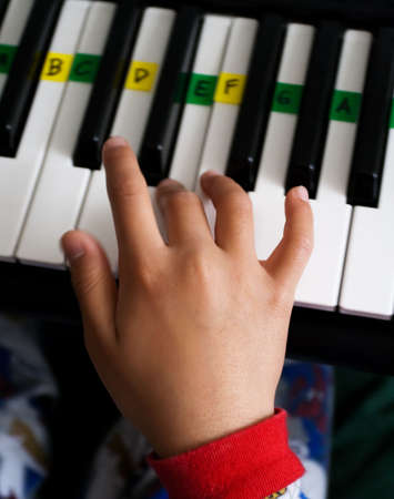 Close up of a childs hand playing on a piano keyboardの写真素材