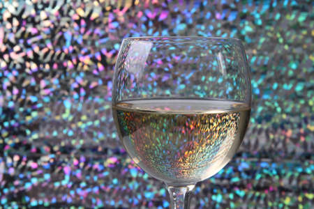 A glass of white wine with multi-colored backgroundの写真素材