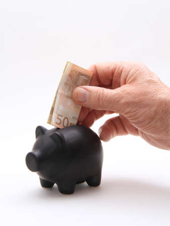A black piggybank with money on a white backgroundの写真素材