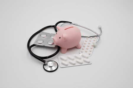 Piggy bank medicines and stethoscope on white backgroundの写真素材