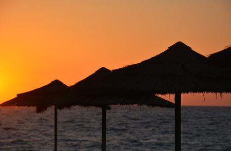 Tropical sunset with beach umbrellas and seaの写真素材
