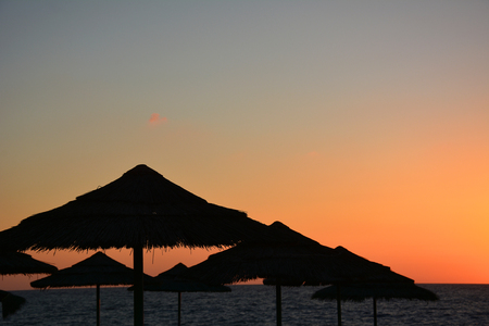 Tropical sunset with beach umbrellas and seaの写真素材