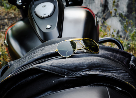 sunglasses on a leather jacket on a motorcycle seat close-upの写真素材