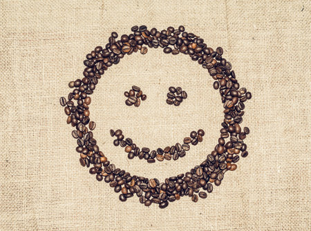 smiling face formed by coffee grains on coarse clothの写真素材