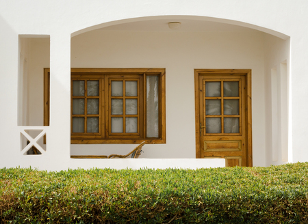 white holiday house with a bush with green leaves nearbyの写真素材