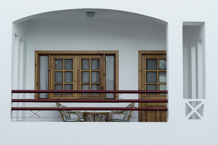 balcony of a white resort house with a window with a door and chairs with a tableの写真素材