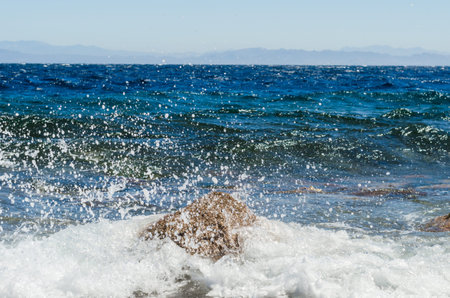 waves and splashes of sea surf and stones on the seashoreの写真素材