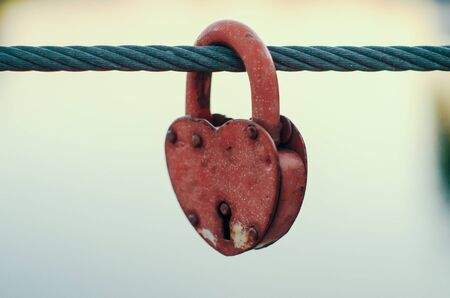 red peeling wedding lock on a rope with a key holeの写真素材