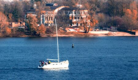 yacht with a tourists on the background of the coast and the city of Kiev Ukraine in the autumn morningの写真素材