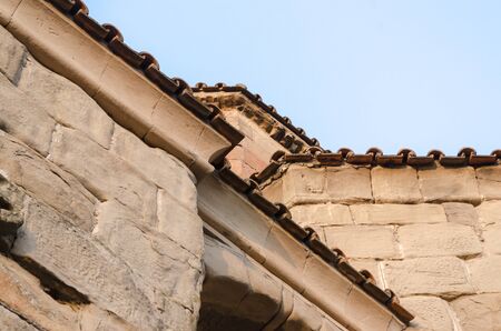 fragment of the wall and roof of an old house on a background of blue skyの写真素材