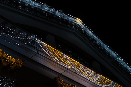 fragment of the facade and roof of a vintage building with colored lights decoration isolated on...