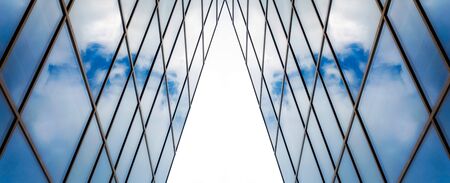 reflection of blue sky with white clouds in a window of a tall office building abstract architectural backgroundの写真素材