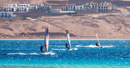 three surfers compete in the Red Sea in the lagoon in Egyptの写真素材