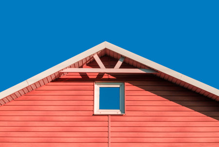 roof of pink farmhouse wooden house against blue sky background rustic architecture