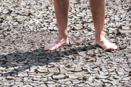 bare feet of a person on dry soil without plants bad ecology and global warmingの写真素材