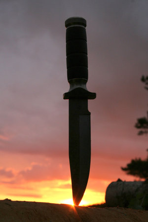 a hunting knife in a lag on a sunset