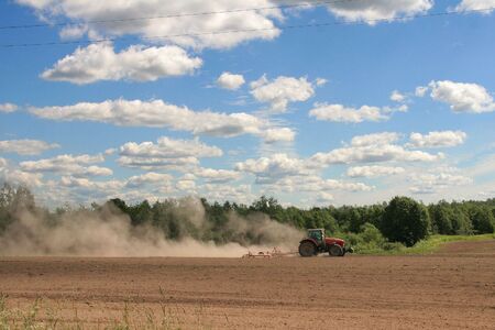 a tractor on a tillage in the daytimeの写真素材