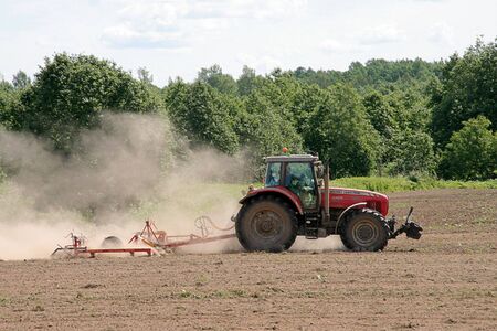 a working tractor on a tillage in a dayの写真素材