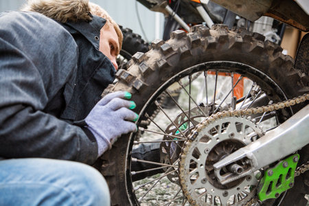 Man tightens a wheel to a motorcycle close upの写真素材