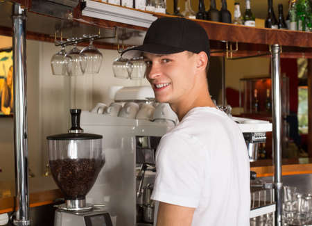 Young handsome smiling barista in white shirt and baseball hat sの写真素材