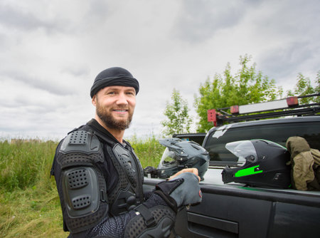 Happy smiling young man outdoors wearing motorcycle gear and loo
