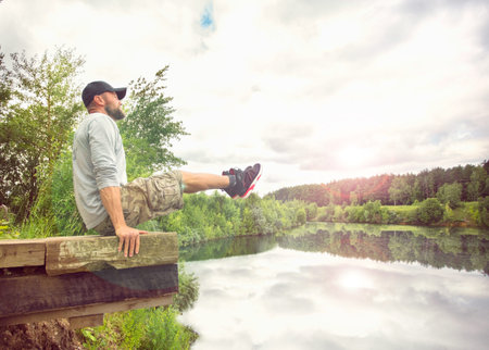 Happy man exercising on a wooden bench and looking at beautiful