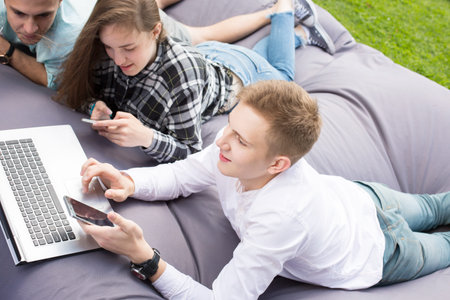 Three young friends laying on a large cushion and chilling outdo