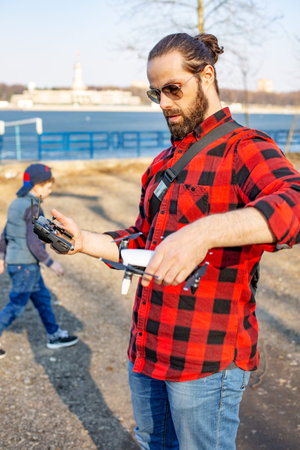 Dad and son playing with drone, man and boy playing with flying drone in park