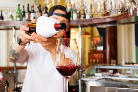Bartender pours a glass of red wine at the bar