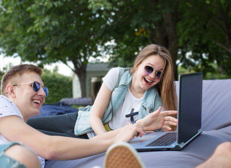 Couple of friends relaxing in the park with laptop.