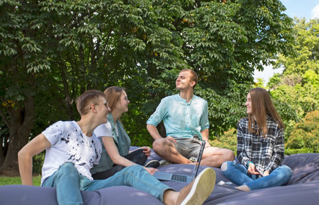 Four  friends relaxing in the park with laptop